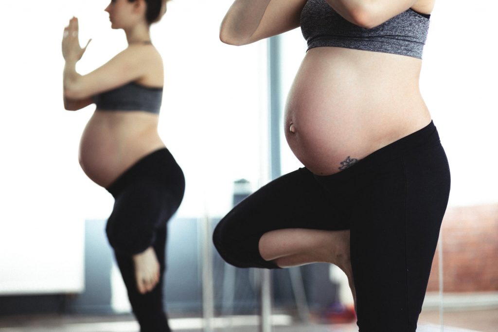 Femme enceinte dans la position de l'arbre pendant une séance de yoga prénatal