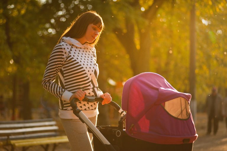 maman qui promène son enfant dans une poussette rose